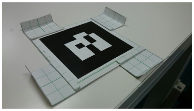 Front of a marker: black square pattern on white card with tabs on each side.