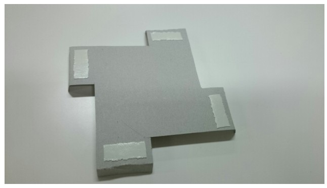 Back of a marker: grey card with white adhesive patches at the tab ends.