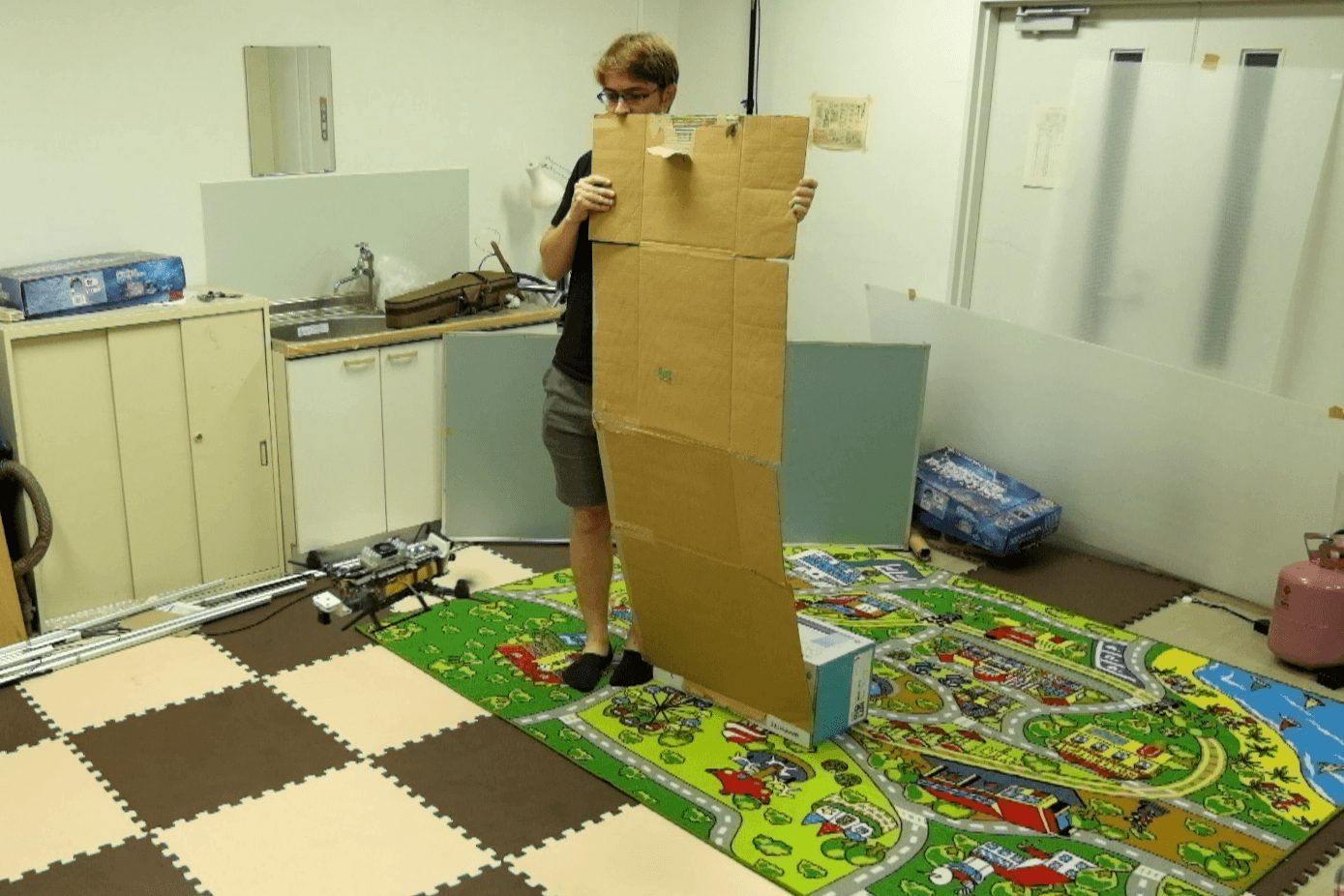 A person holding up a cardboard board in front of the drone